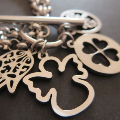 Pendentes de metal prateado com formas de folha, trevo e coração numa corrente