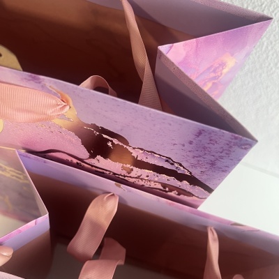 Sacolas de presente rosa com alças de fita e detalhes dourados