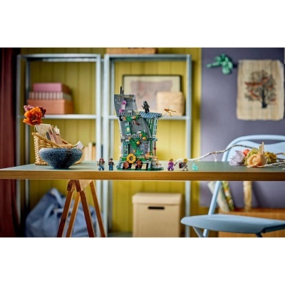 Conjunto de construção torre cinzenta com minifiguras coloridas numa mesa de madeira