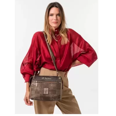Mulher com camisa vermelha e mala castanha com padrão texturizado e gravação dourada