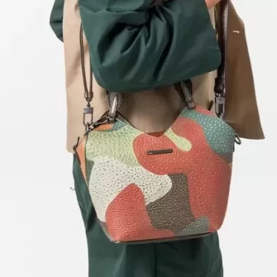 Bolsa de ombro com padrão camuflado colorido e textura granulada.