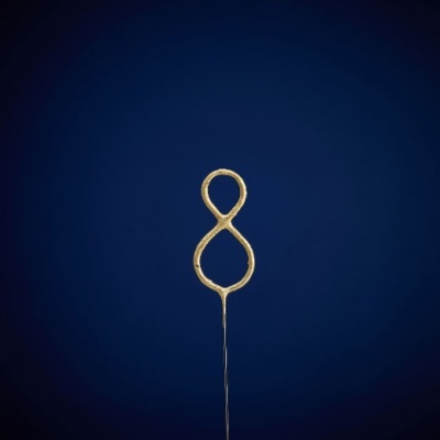 Aparato dourado em formato de oito deitado com haste fina sobre fundo azul escuro