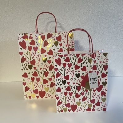 Duas sacolas de papel com corações coloridos e etiqueta 100% RECICLÁVEL