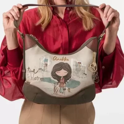 Mala de ombro castanha e bege com ilustração de rapariga e textos, segurada por pessoa com camisa vermelha.