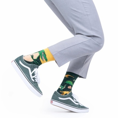 Meias com desenhos de dinossauros em cores amarelo e verde usadas com ténis verde oliva e calças cinza claro