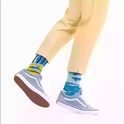 Meias coloridas com padrão de peixes azuis e amarelos com sapatilhas cinza.