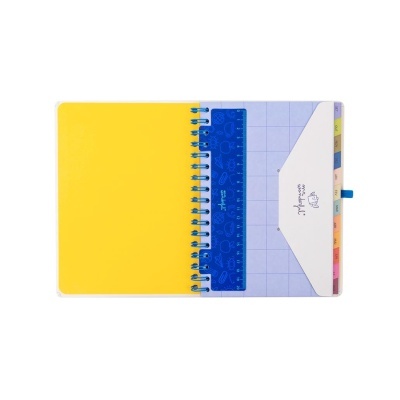 Caderno espiral amarelo aberto com folhas quadriculadas, régua azul e envelope branco com texto.