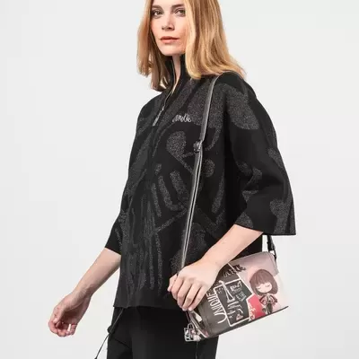 Mulher com blusa preta e bolsa tiracolo bege estampada