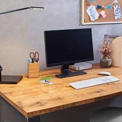 Secretária de madeira com computador, candeeiro, material de escritório e painel de cortiça