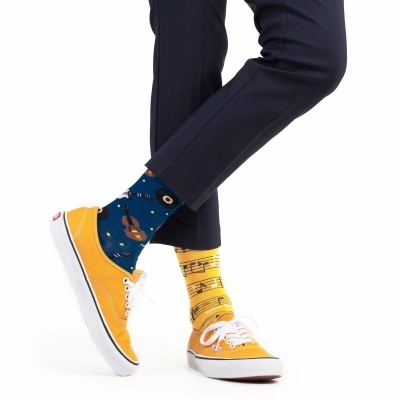 Meias coloridas musicais com sapatos amarelos e calças pretas.