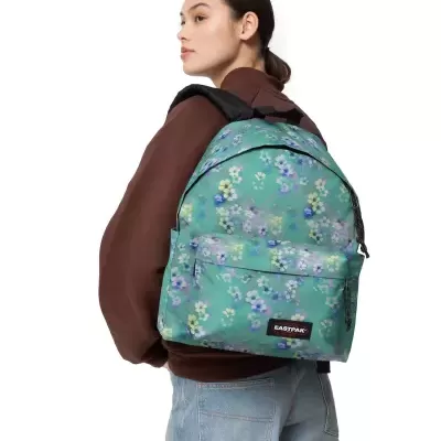Mochila floral verde Eastpak usada por pessoa com casaco castanho e jeans azuis