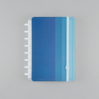 Caderno azul com fecho branco e argolas visíveis sobre fundo cinza.