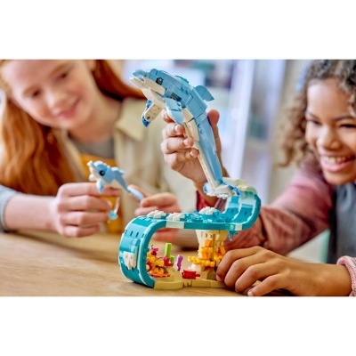 Crianças a brincar com conjunto de blocos de construção de golfinhos e recife de coral.