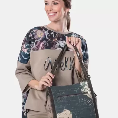 Mulher segurando mala floral castanha com alças de couro sintético castanho