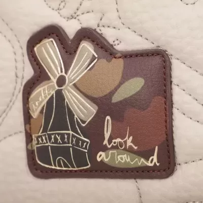 Etiqueta de patch em pele creme com moinho e texto em pele castanha