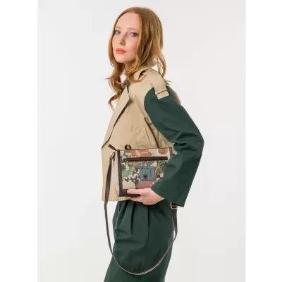 Mulher com casaco bege e verde segura bolsa camuflada com desenho de gato.