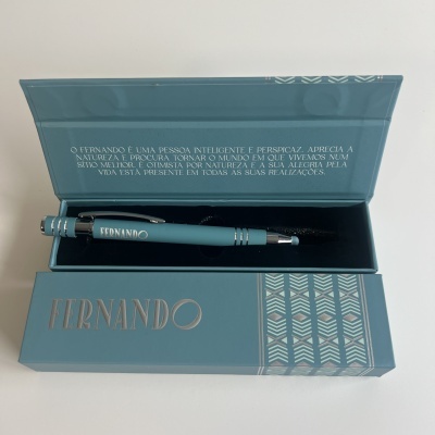 Caneta azul turquesa dentro de caixa azul com nome Fernando e texto no interior