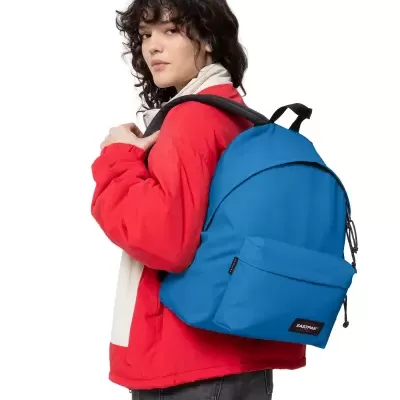 Mochila azul Eastpak com bolso frontal usada por pessoa com casaco vermelho