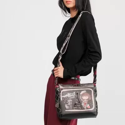 Mulher com mala de ombro preta e cinza com ilustração frontal