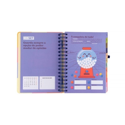 Agenda aberta com texto em português, calendário e ilustração colorida de máquina de bolinhas.