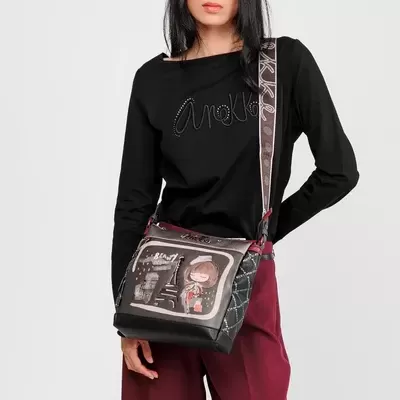 Mulher com top preto, calças vinhas largas e bolsa preta estampada