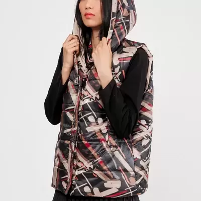 Colete acolchoado com capuz e padrão abstracto multicolorido usado por mulher com vestido preto