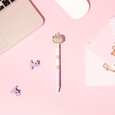 Caneta decorada com gato em superfície rosa com acessórios de escritório