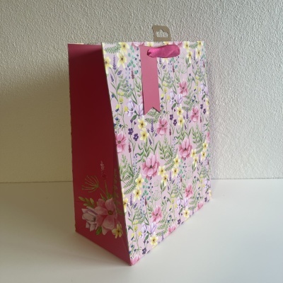 Saco de papel rosa com padrão floral e alça de fita rosa