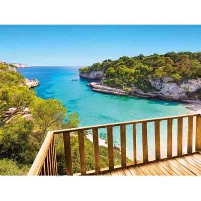 Vista de baía azul-turquesa rodeada por falésias e vegetação verde vista de varanda de madeira