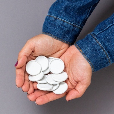 Mãos seguram ímanes brancos redondos sobre fundo cinzento