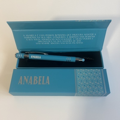 Caneta azul dentro de caixa azul com texto 'ANABELA' e padrão geométrico