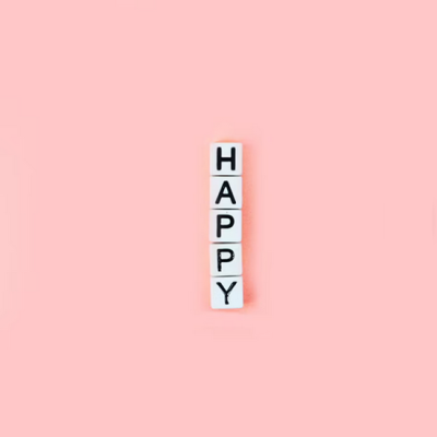 Blocos brancos com letras pretas a formar a palavra HAPPY sobre fundo rosa