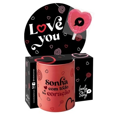 Caneca rosa com frase e padrão de corações embalada em caixa preta decorada com corações e texto Love you, com pirulito em forma de coração.