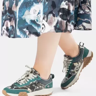 Ténis femininos verdes com padrão floral e sola castanha, usados com saia azul