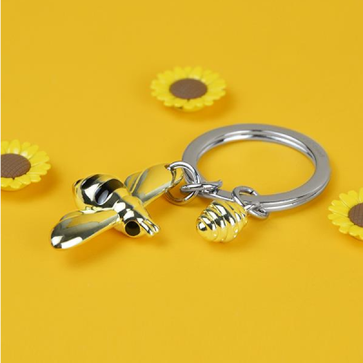 Chaveiro com abelha e favo dourados em fundo amarelo com girassóis