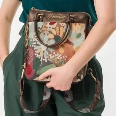 Mala de ombro floral Anokhi em material misto castanho segurada por pessoa