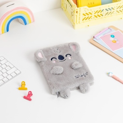 Caderno cinzento com capa peluda de coala sobre mesa com office supplies