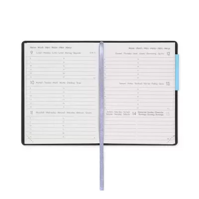 Agenda semanal aberta com capa preta, páginas brancas com texto impresso e fita marcadora roxa