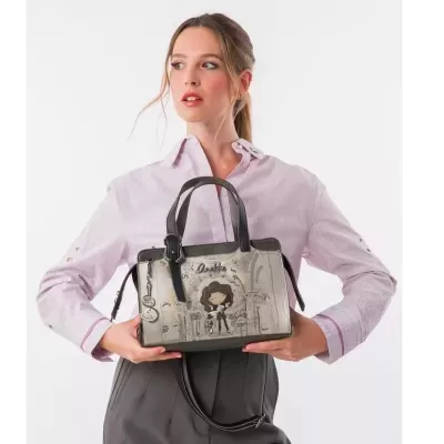 Mala de mão retangular cinza e preta com ilustração de menina, segurada por mulher com camisa rosa clara e calças cinzentas