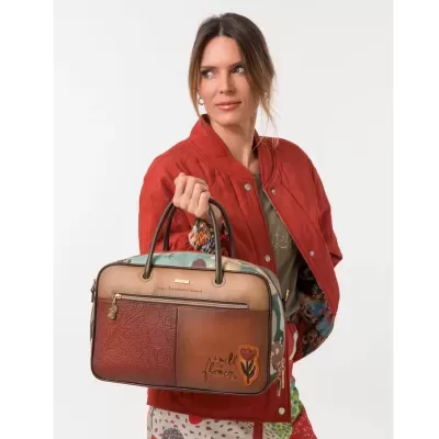 Mala de mão feminina castanha com estampado floral e escrita Wild flower, segurada por mulher de casaco vermelho