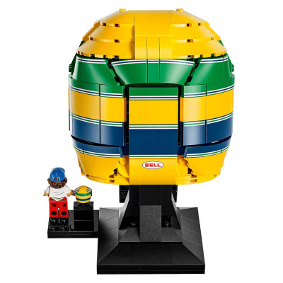 Capacete de plástico estilo LEGO colorido em amarelo, verde e azul com mini figura e suporte preto.