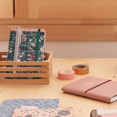 Cadernos e fitas adesivas sobre mesa de madeira clara