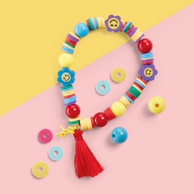 Pulseira colorida com contas redondas, flores sorridentes e borla vermelha sobre fundo amarelo e rosa
