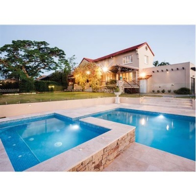 Piscina exterior em casa com telhado vermelho e iluminação ao entardecer