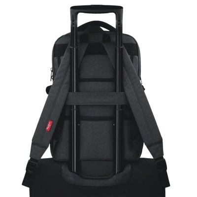 Mochila cinzenta escura com alças e etiqueta vermelha, presa à mala preta.