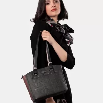 Mulher a segurar bolsa preta com padrão em relevo e detalhes castanhos