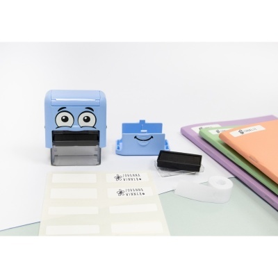 Selo azul com olhos, carimbo, etiquetas JOHANNA WINNER e cadernos coloridos.