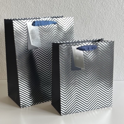 Duas sacolas de presente metálicas prateadas com padrão de zig-zag