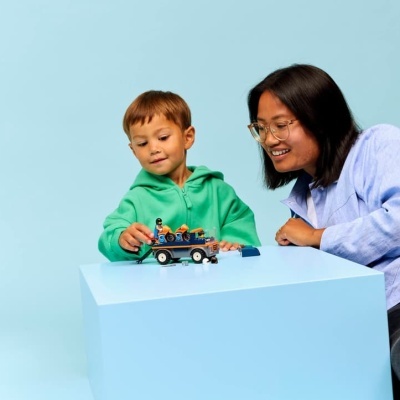 Criança e adulta a brincar com brinquedo de construção e figuras miniaturas