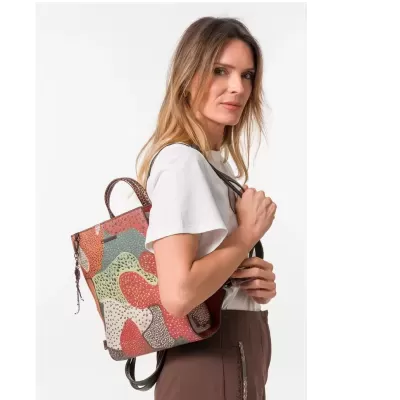 Mulher com mochila estampada colorida, t-shirt branca e calças castanhas